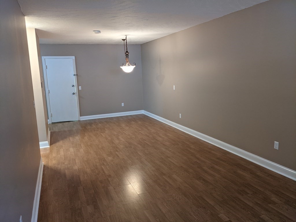 72 Leonard Road, Unit 72 Boxborough, MA 01719 - Photo 7 of 25 an empty room with wooden floor and mirror