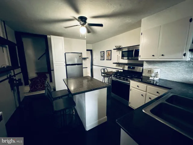 a kitchen with stainless steel appliances granite countertop a stove a refrigerator a sink a microwave counter space and cabinets