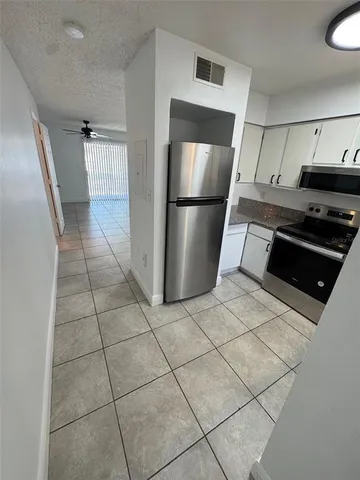 a kitchen with granite countertop a refrigerator and a stove top oven