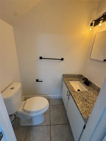 a bathroom with a granite countertop toilet sink and mirror