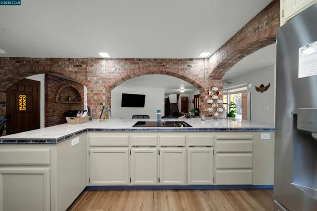 a kitchen with stainless steel appliances kitchen island hardwood floor sink stove dining table and chairs