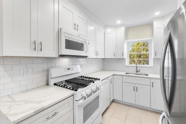 a kitchen with stainless steel appliances granite countertop white cabinets granite counter tops and a window
