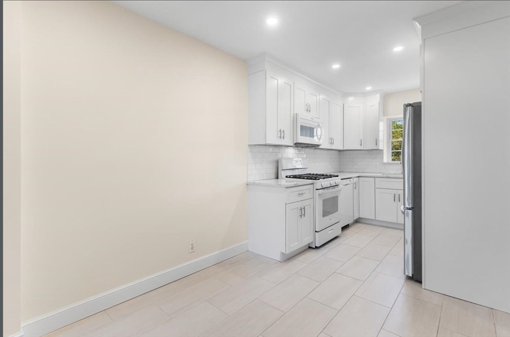 30 Lake Shore Court, Unit 1 Boston, MA 02135 - Photo 8 of 15 a kitchen with white cabinets and white appliances
