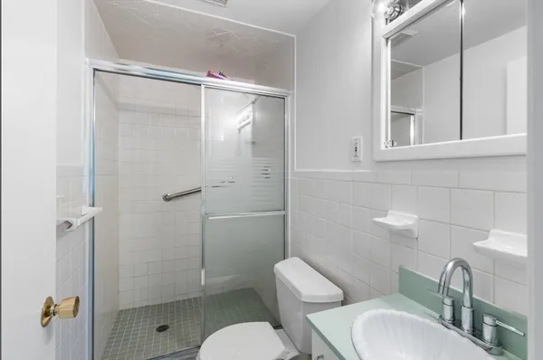 a bathroom with a toilet sink vanity and shower