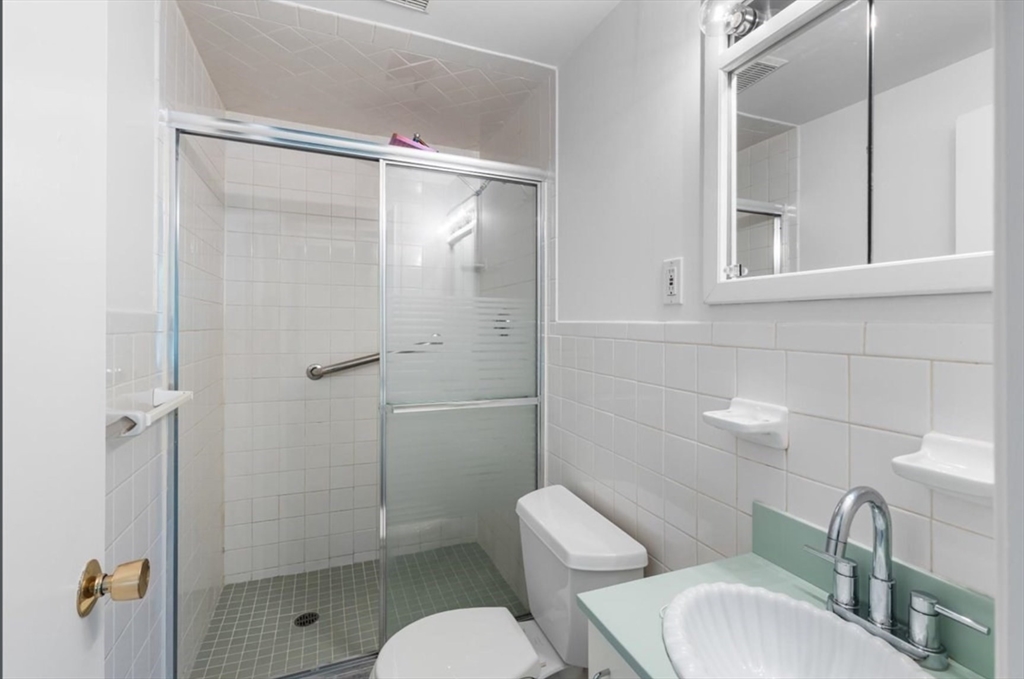 30 Lake Shore Court, Unit 1 Boston, MA 02135 - Photo 9 of 15 a bathroom with a toilet sink vanity and shower