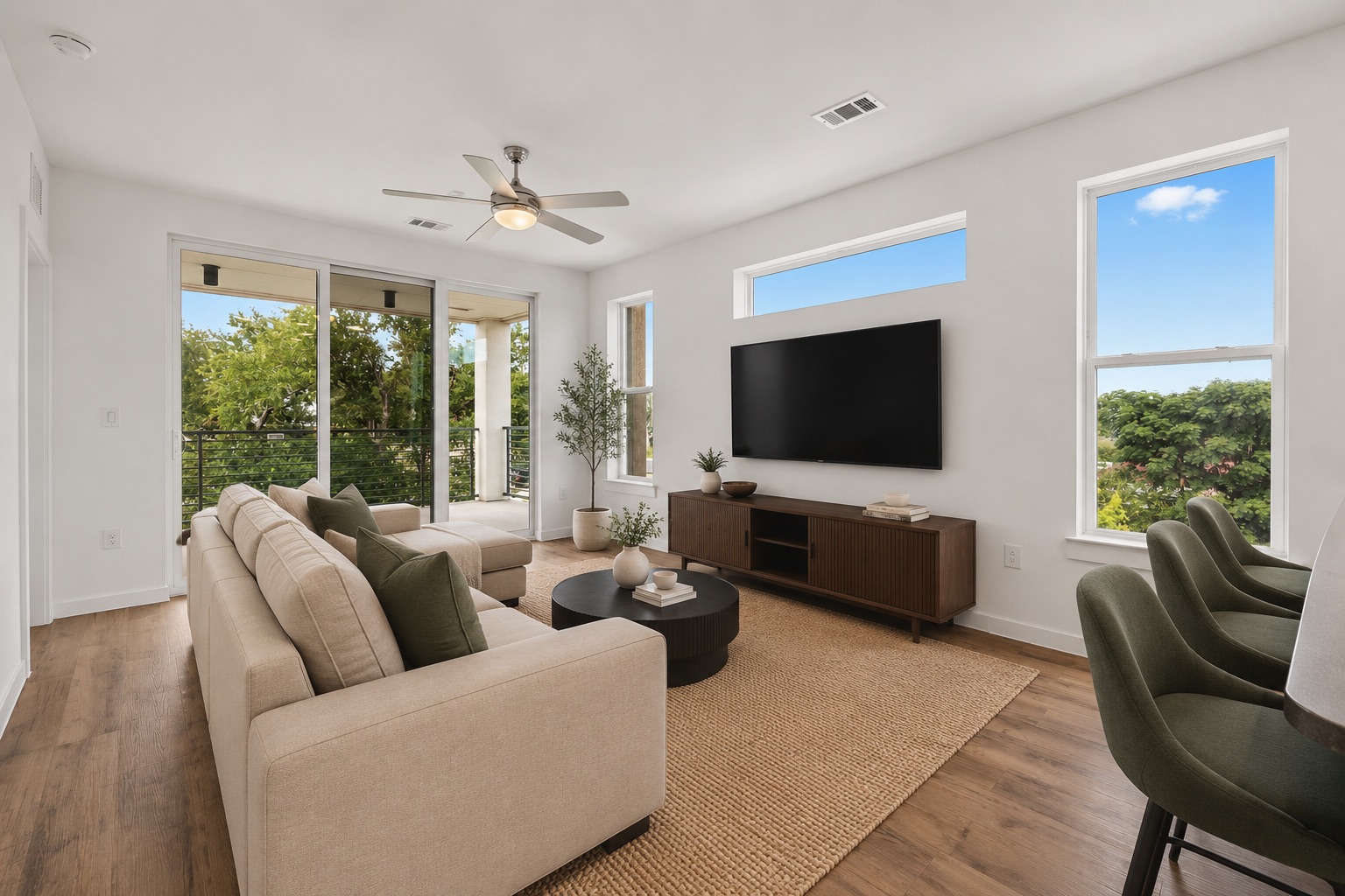 4801 Springdale Road, Unit 2301 Austin, TX 78723 - Photo 8 of 36 Natural light floods this living area, offering wood flooring, a ceiling fan, and access to an outdoor balcony.