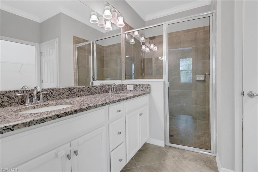 9108 Glenforest Drive Naples, FL 34120 - Photo 8 of 26 Full bath with ornamental molding, a sink, an inviting chandelier, and a shower stall