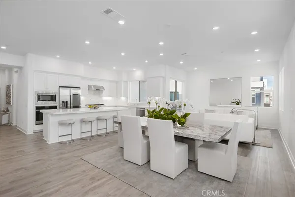 a living room with stainless steel appliances kitchen island granite countertop lots of white furniture a dining table and chairs