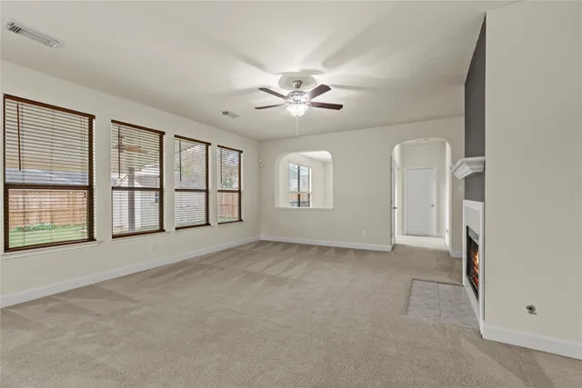 an empty room with chandelier fan and windows