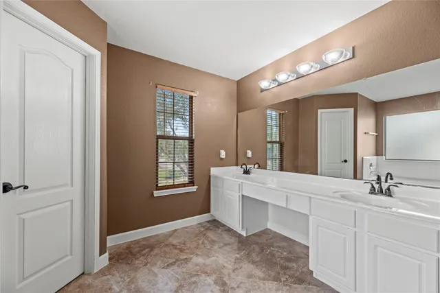 a spacious bathroom with a double vanity sink a mirror and a bathtub