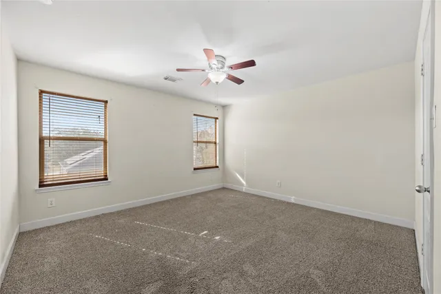 an empty room with windows and fan
