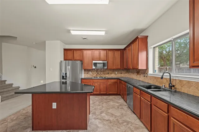 a kitchen with stainless steel appliances granite countertop a sink stove and refrigerator
