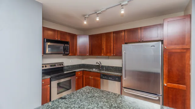 a kitchen with stainless steel appliances granite countertop a stove a sink and a refrigerator