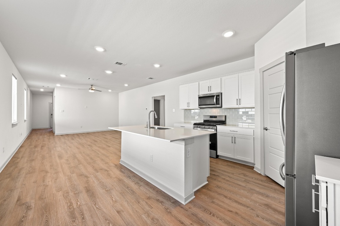 407 Wilshire Road San Marcos, TX 78666 - Photo 14 of 25 a kitchen with white cabinets stainless steel appliances and wooden floor
