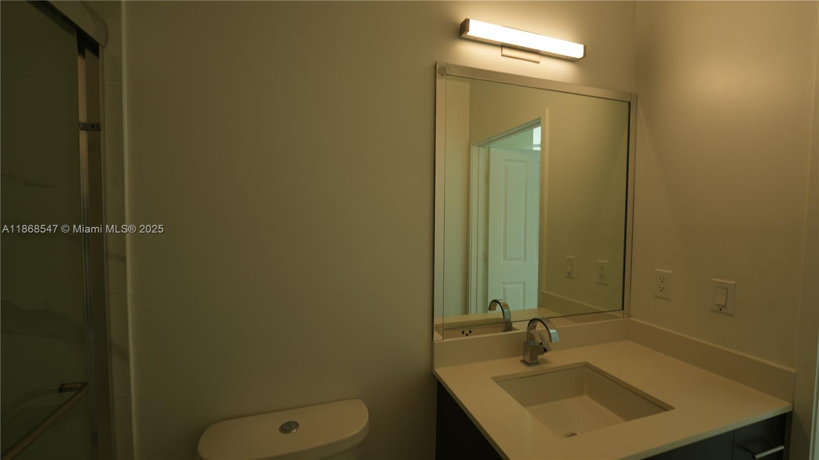 729 Northwest 2nd Street, Unit 717 Miami, FL 33128 - Photo 23 of 25 a bathroom with a sink a toilet and a mirror