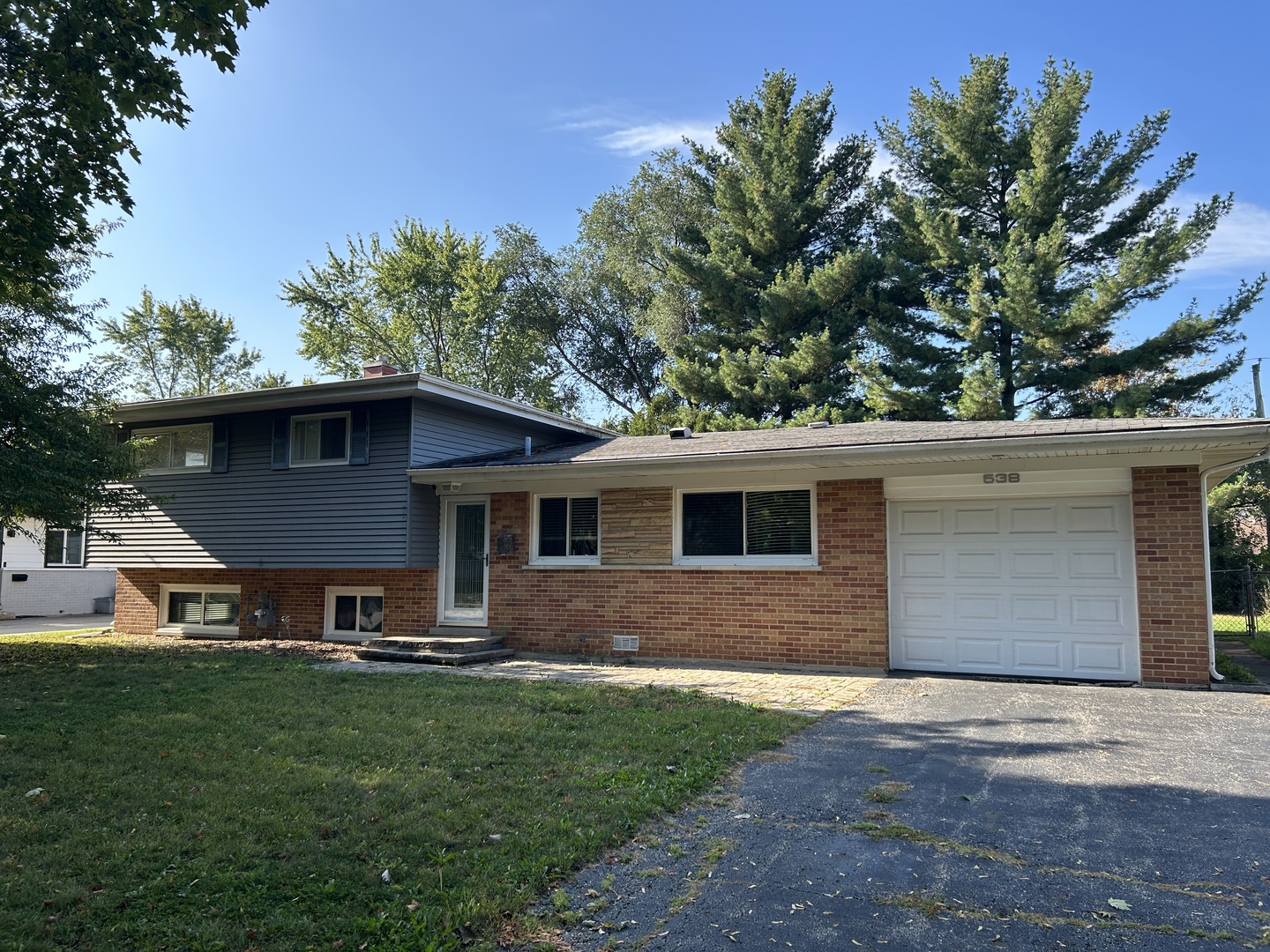 a front view of house with yard and trees in the background