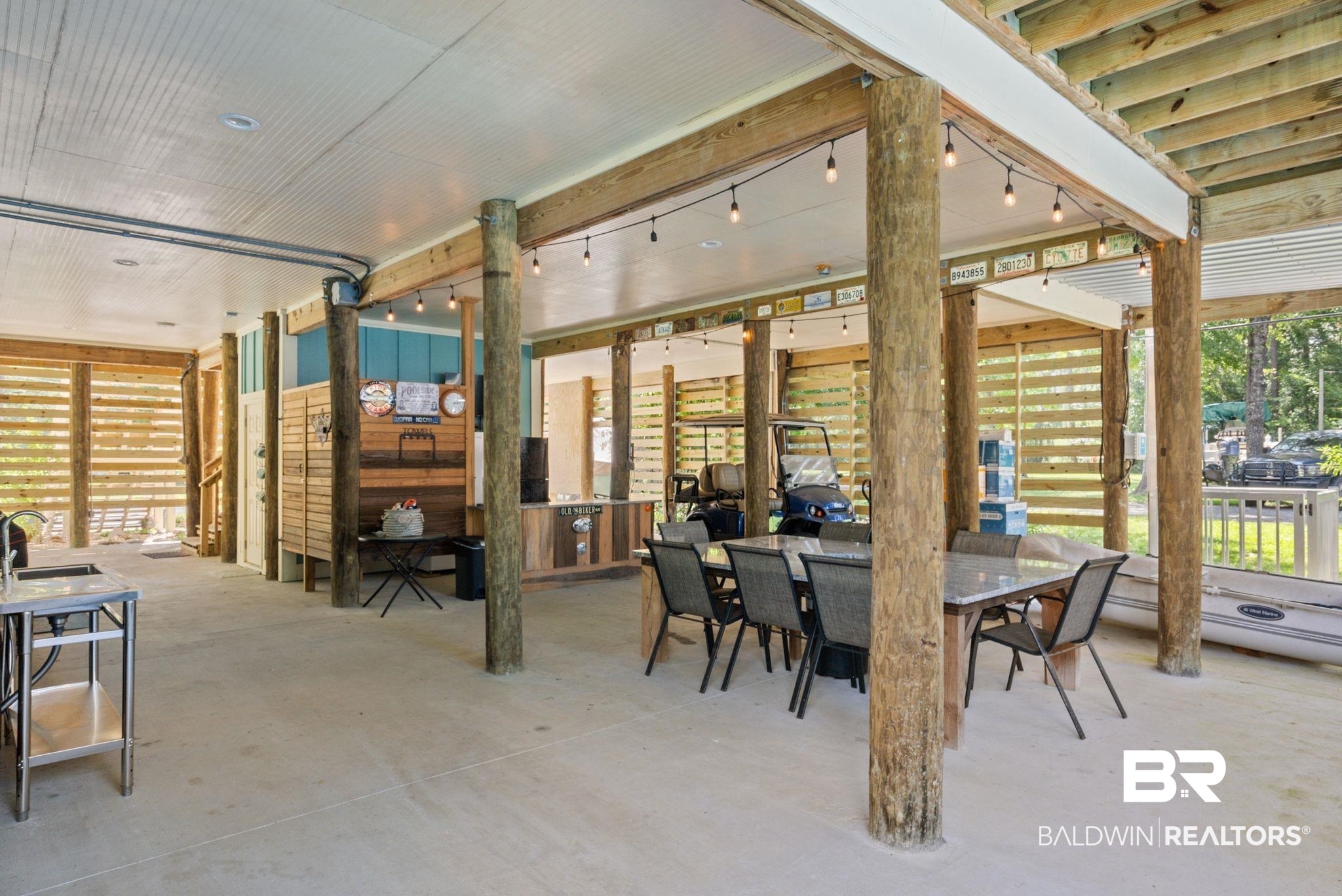 7266 Franklin Road Foley, AL 36535 - Photo 54 of 64 Spacious covered patio featuring robust wood columns, a built-in wood-paneled bar area, concrete flooring, and perimeter string lighting