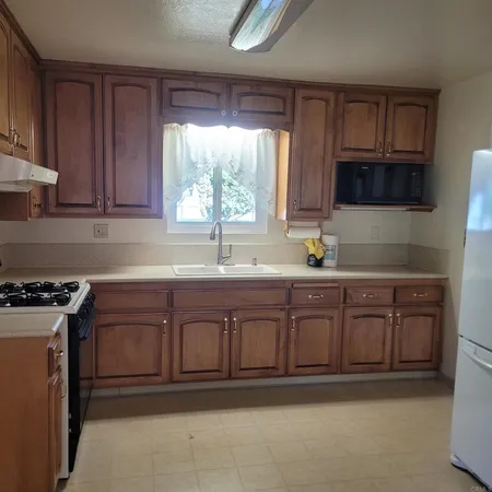 a kitchen with stainless steel appliances granite countertop a sink a stove a microwave cabinets and a window