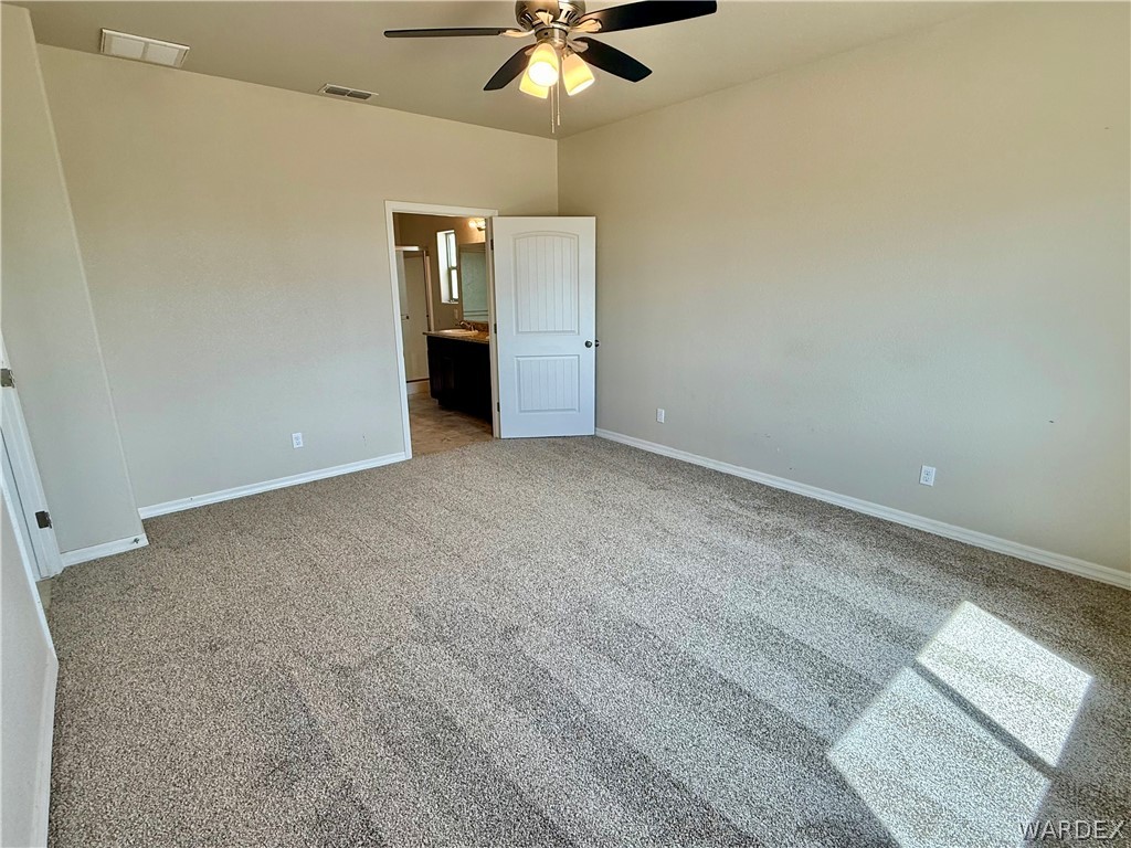 5392 Rattlesnake Road Kingman, AZ 86409 - Photo 17 of 35 an empty room with a ceiling fan and carpet