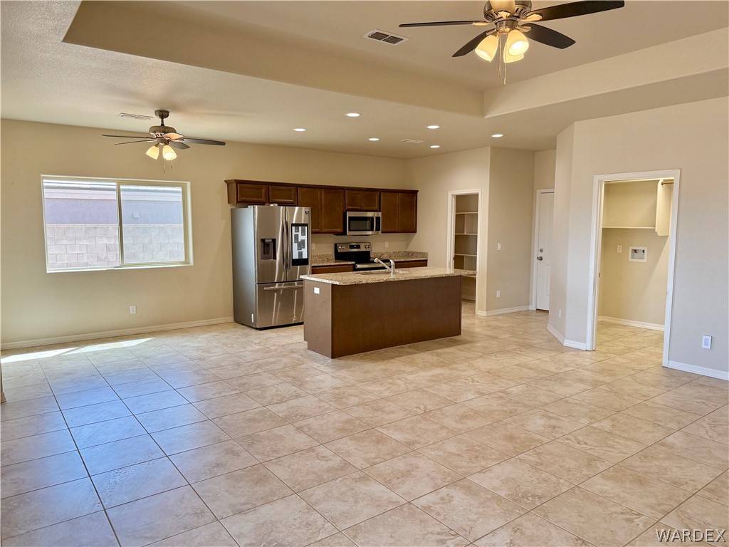5392 Rattlesnake Road Kingman, AZ 86409 - Photo 10 of 35 a view of a livingroom with a ceiling fan a kitchen a refrigerator and a chandelier