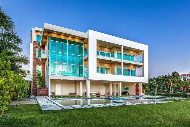 a view of a swimming pool with lawn chairs and a large tree