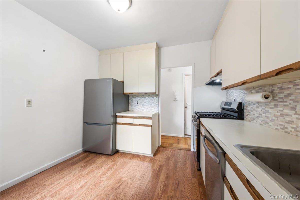 281 Garth Road, Unit C2H Scarsdale, NY 10583 - Photo 29 of 38 a kitchen with stainless steel appliances granite countertop a refrigerator a sink dishwasher a stove and white countertops with wooden floor