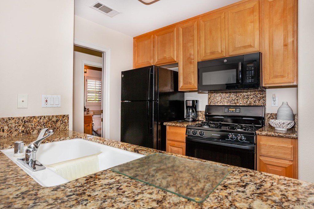 5560 Foxtail Loop Carlsbad, CA 92010 - Photo 24 of 32 a kitchen with granite countertop a stove top oven microwave and refrigerator
