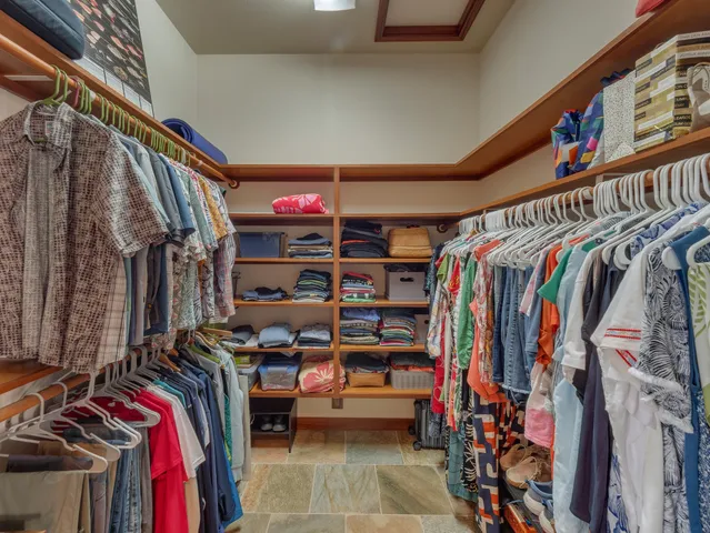 a view of walk in closet with clothes and shoes