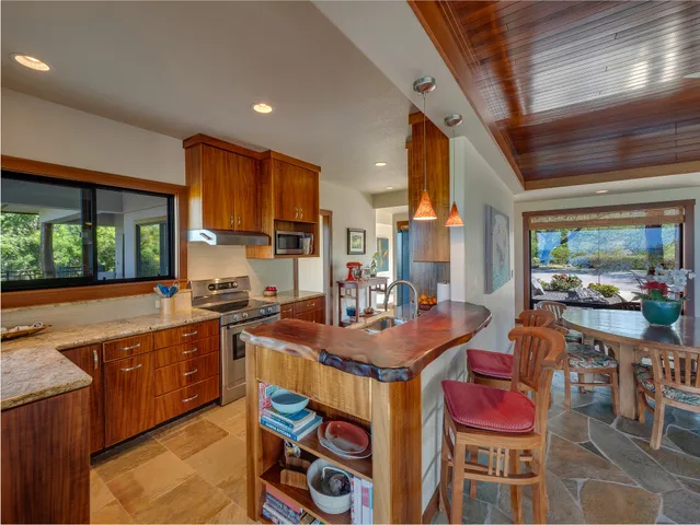 a dining hall with stainless steel appliances kitchen island granite countertop a dining table and chairs