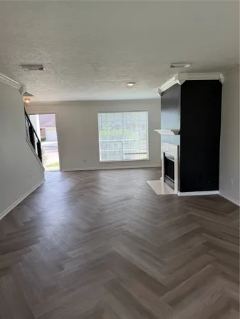 an empty room with wooden floor cabinet and windows
