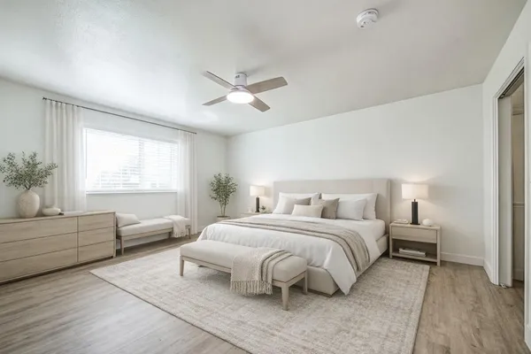 a bedroom with a large bed couch and windows