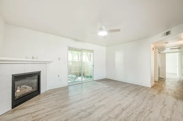 an empty room with wooden floor fireplace and windows