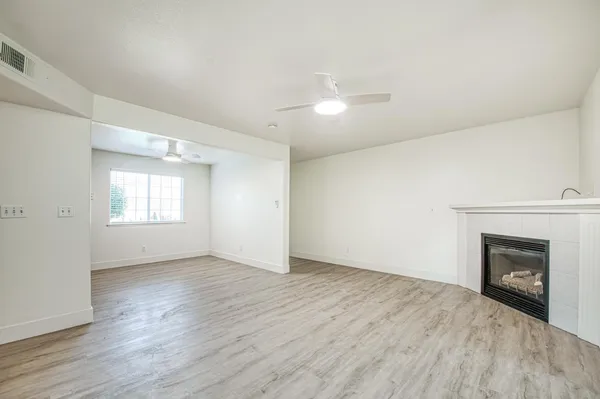 an empty room with wooden floor fireplace and windows