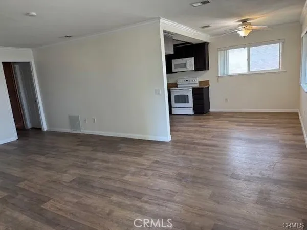an empty room with wooden floor and stainless steel appliances