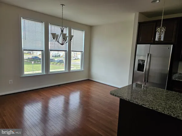 a kitchen with stainless steel appliances granite countertop a refrigerator a stove and a wooden floors