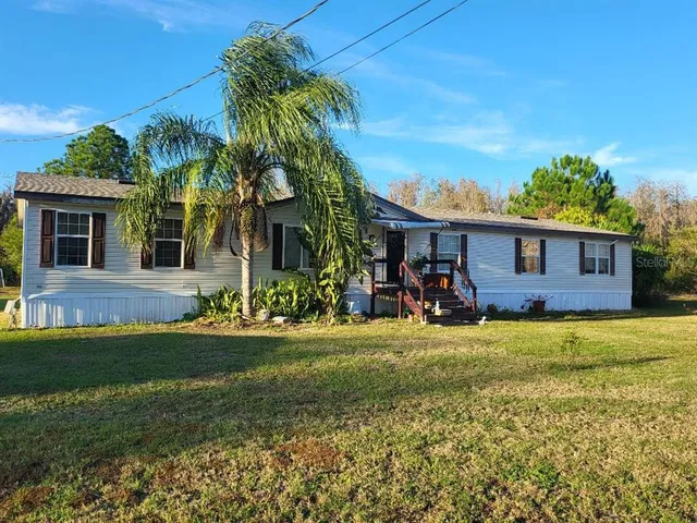 a view of a house with a yard and palm trees