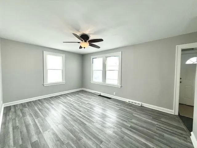 a view of an empty room with a window and wooden floor