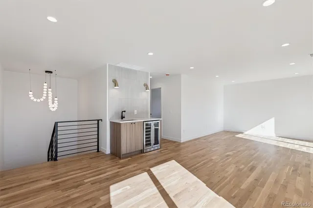 a view of kitchen and empty room with wooden floor