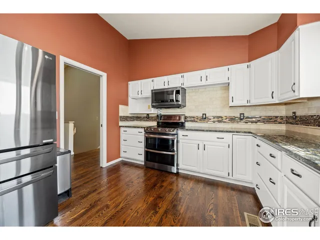 a kitchen with stainless steel appliances white cabinets and wooden floor