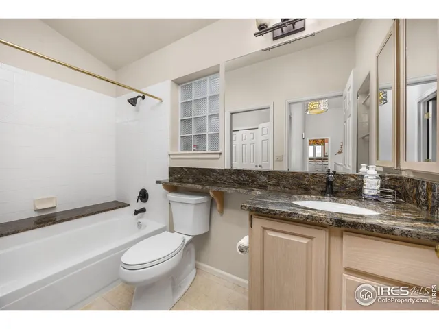 a bathroom with a granite countertop sink a toilet a mirror and bathtub