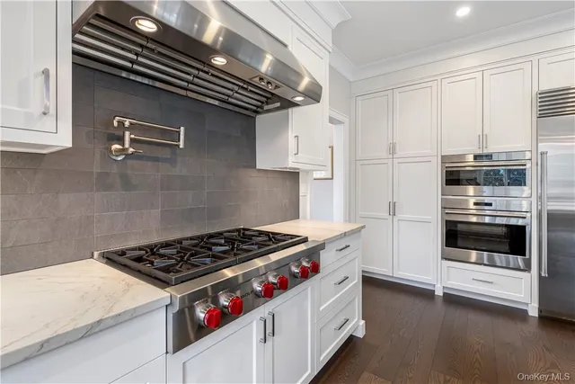 a kitchen with stainless steel appliances a stove and white cabinets