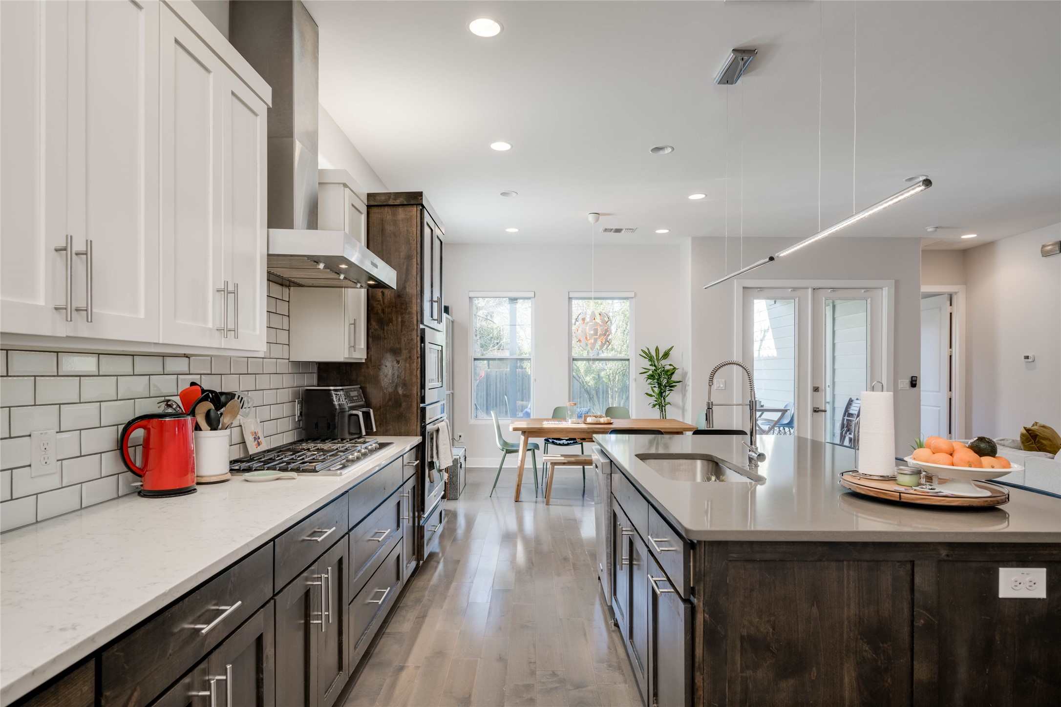 7514 Hardy Drive Austin, TX 78757 - Photo 4 of 29 Kitchen with dual tone cabinetry, light stone countertops, tasteful backsplash, a large island, and pendant lighting