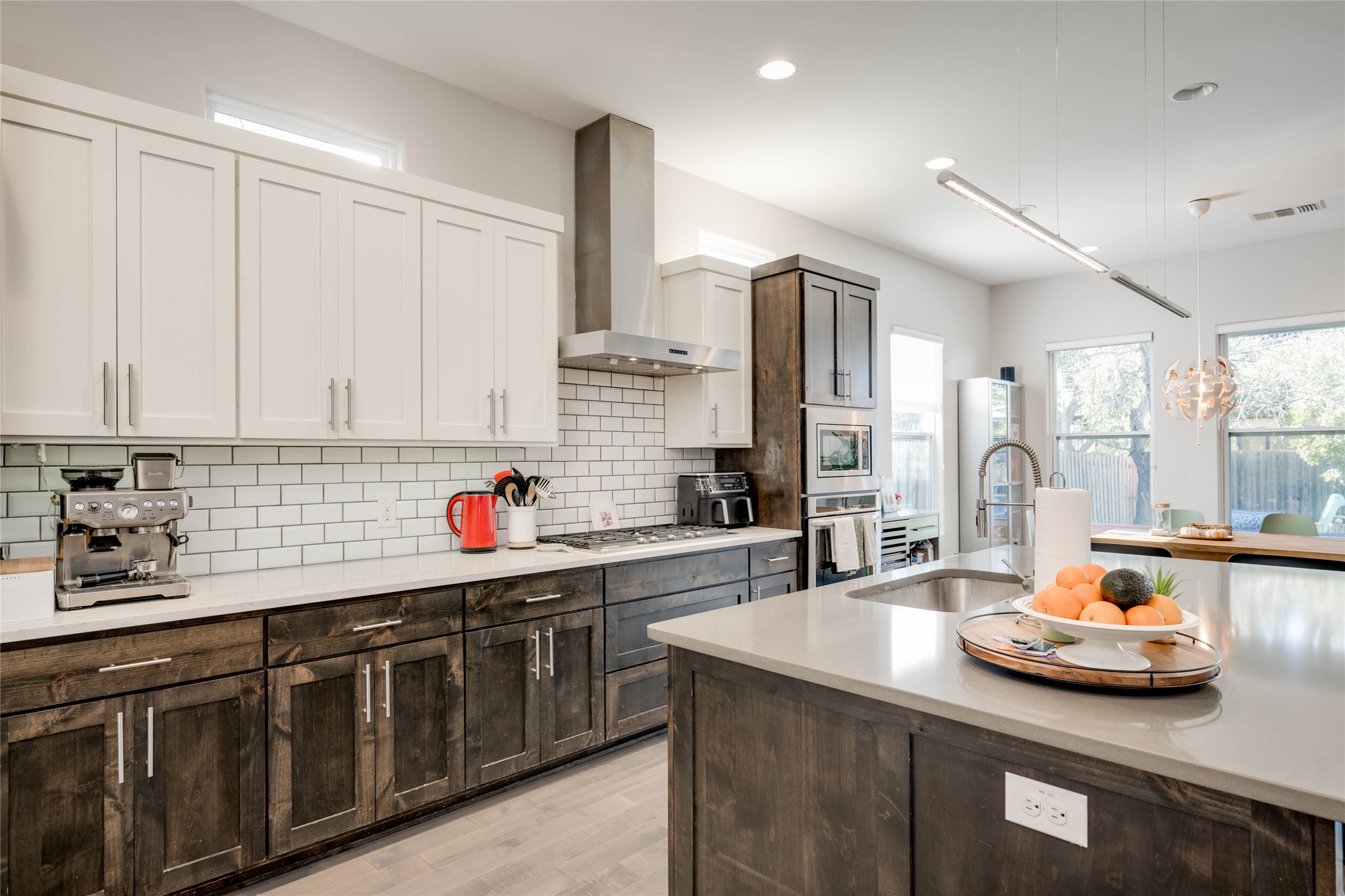 7514 Hardy Drive Austin, TX 78757 - Photo 8 of 29 Kitchen with two tone color scheme, stainless steel appliances, light wood finished floors, backsplash, and light stone counters
