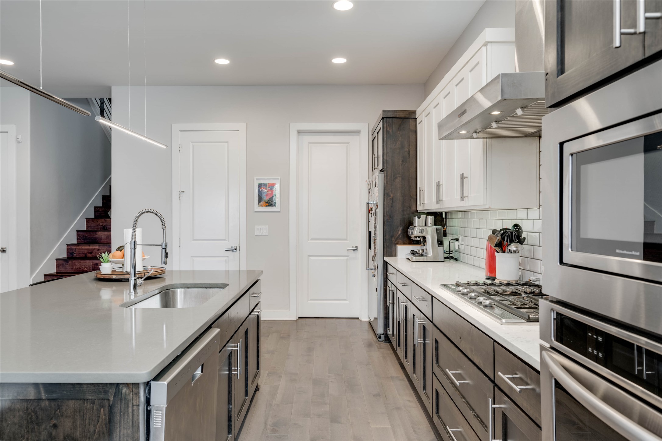 7514 Hardy Drive Austin, TX 78757 - Photo 9 of 29 Dual tone kitchen featuring dual tone cabinetry, light stone countertops, tasteful backsplash, light wood-style floors, and stainless steel appliances