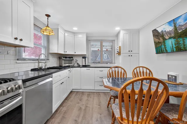 a kitchen with granite countertop a stove top oven a sink dishwasher and white cabinets with wooden floor