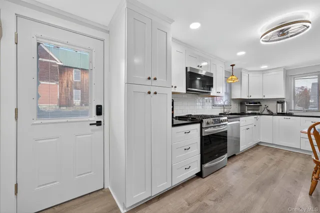 a kitchen with granite countertop white cabinets and stainless steel appliances