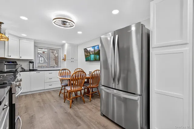 a kitchen with stainless steel appliances granite countertop a refrigerator a stove a sink a dining table and chairs with wooden floor