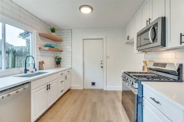 a kitchen with cabinets appliances a sink and a window