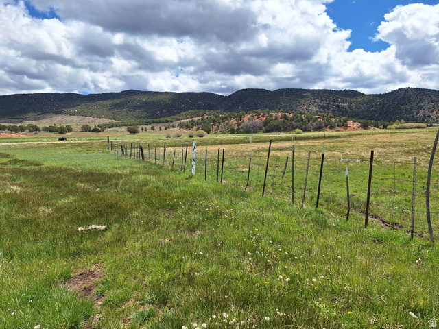 Expansive land parcel featuring open fields, a wire fence, and distant treed hills