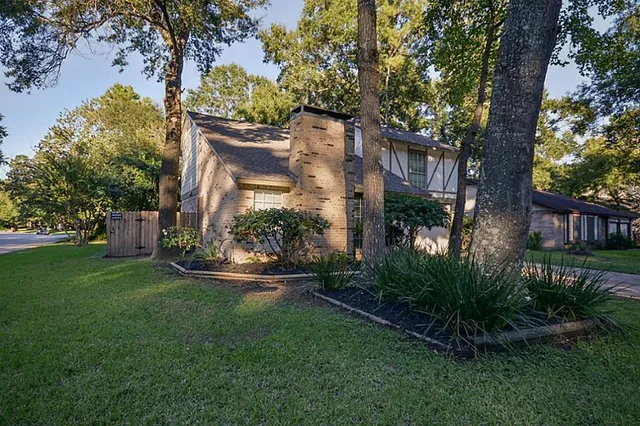 a view of a white house next to a yard with plants and trees